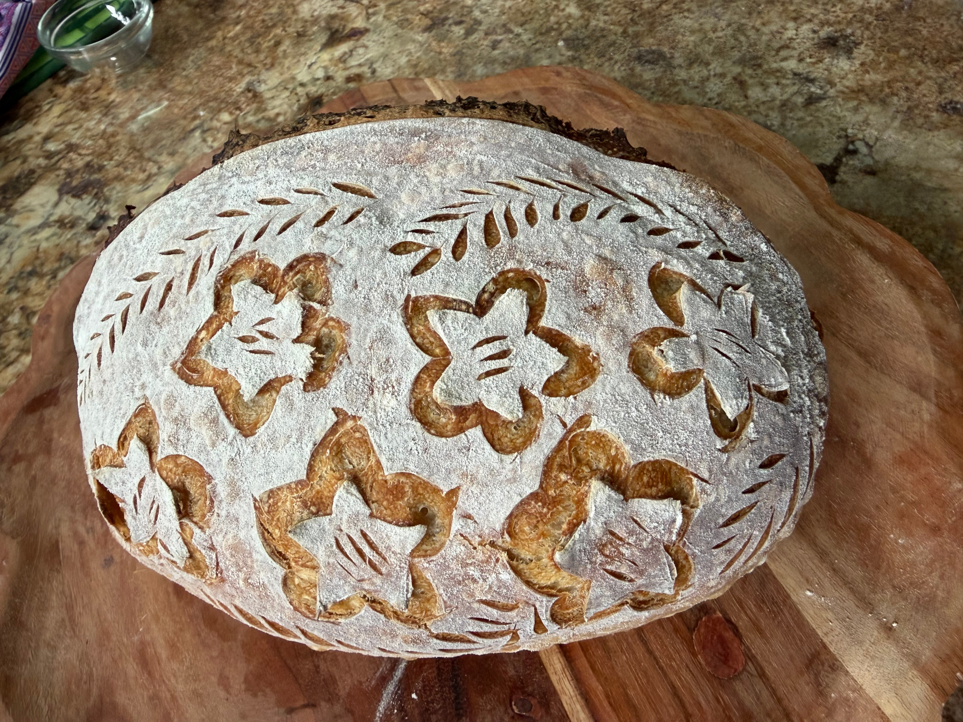 A finished sourdough loaf scored with floral patterns
